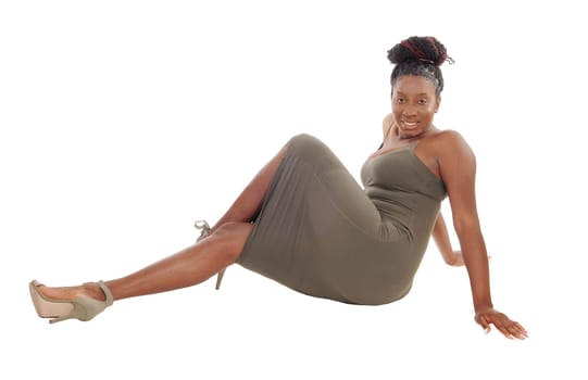 A beautiful tall African American woman sitting in a gray dress.on the floor in the studio, isolated for white background.