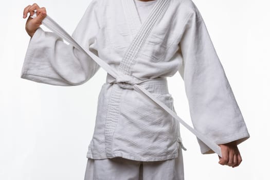 Stages of correct tying of the belt by a teenager on a sports kimono, step nine