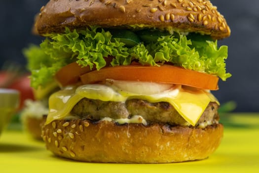 Two hamburgers close-up on a round wooden board, next to, tomatoes, chopped onions and spinach leaves.