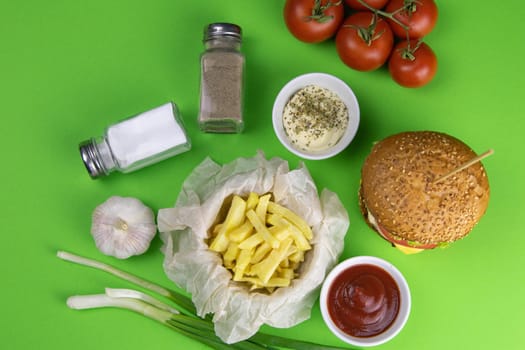 Two hamburgers close-up on a round wooden board, next to, tomatoes, chopped onions and spinach leaves.