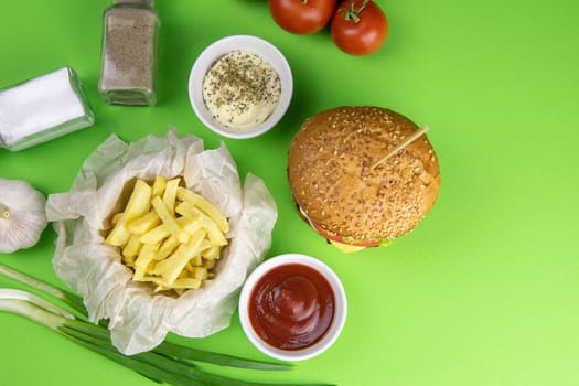 Two hamburgers close-up on a round wooden board, next to, tomatoes, chopped onions and spinach leaves.