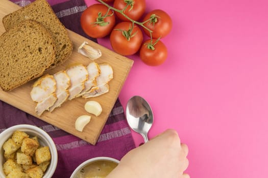 Pea soup with croutons stands on a green towel, next to there are tomatoes, toasts of pumpkin seeds, everything stands on the yellow table.
