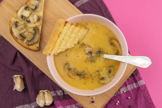 Pea soup with croutons stands on a green towel, next to there are tomatoes, toasts of pumpkin seeds, everything stands on the yellow table.