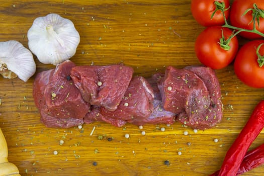 Preparing for the preparation of hamburgers. On a wooden board are lettuce leaves, chopped: tomatoes, cucumbers, onions, cutlets and sauces.