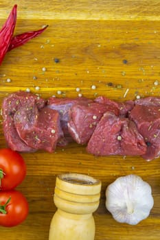 Preparing for the preparation of hamburgers. On a wooden board are lettuce leaves, chopped: tomatoes, cucumbers, onions, cutlets and sauces.