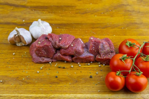 Preparing for the preparation of hamburgers. On a wooden board are lettuce leaves, chopped: tomatoes, cucumbers, onions, cutlets and sauces.