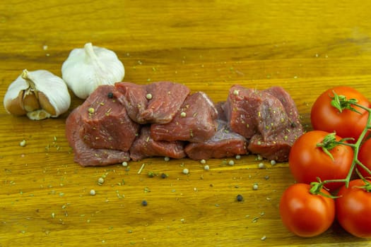 Preparing for the preparation of hamburgers. On a wooden board are lettuce leaves, chopped: tomatoes, cucumbers, onions, cutlets and sauces.