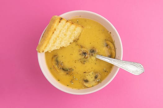 Pea soup with croutons stands on a green towel, next to there are tomatoes, toasts of pumpkin seeds, everything stands on the yellow table.