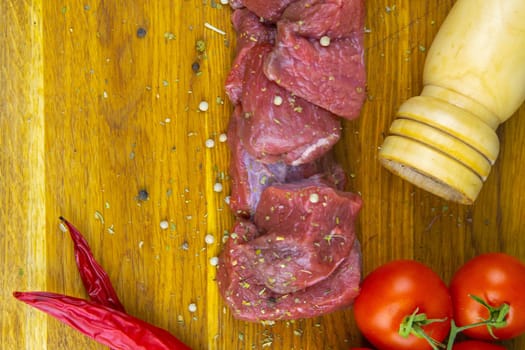 Preparing for the preparation of hamburgers. On a wooden board are lettuce leaves, chopped: tomatoes, cucumbers, onions, cutlets and sauces.