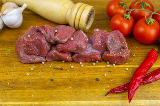 Preparing for the preparation of hamburgers. On a wooden board are lettuce leaves, chopped: tomatoes, cucumbers, onions, cutlets and sauces.