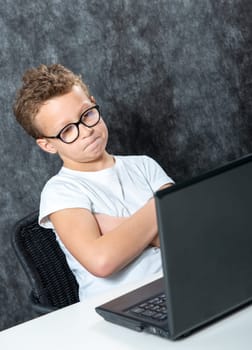 serious boy sitting with a laptop computer