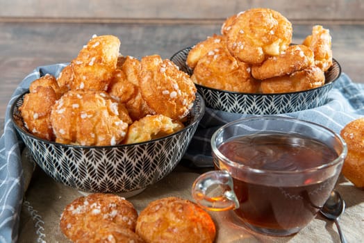 Chouquette, french choux pastry and cup of tea on the wooden table