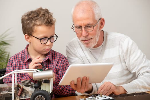 grandpa and son little boy repairing a model radio-controlled car at home