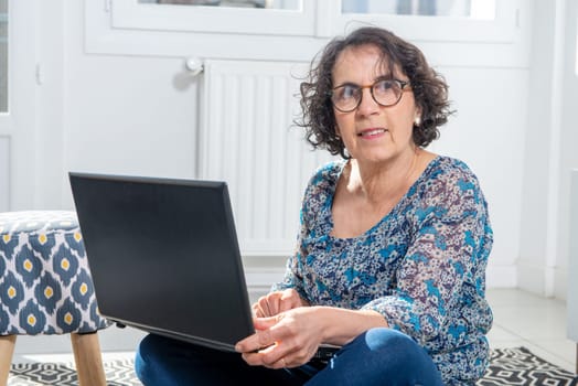 Portrait of a beautiful brunette mature woman with a laptop at home.