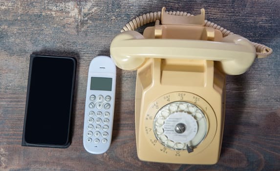 retro phone and new cell phone on the wooden board