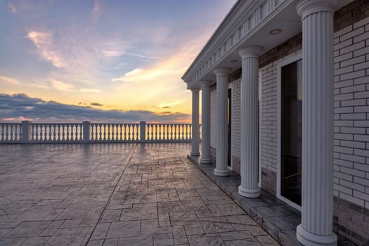 Beautiful building with columns on a landscaped promenade at sunset
