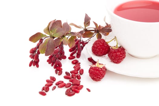 Healthy fruit tea with barberries and raspberries in white cup and branch of berberry isolated on white background.