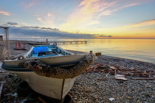 An old boat on the beach against the backdrop of a beautiful sea sunset