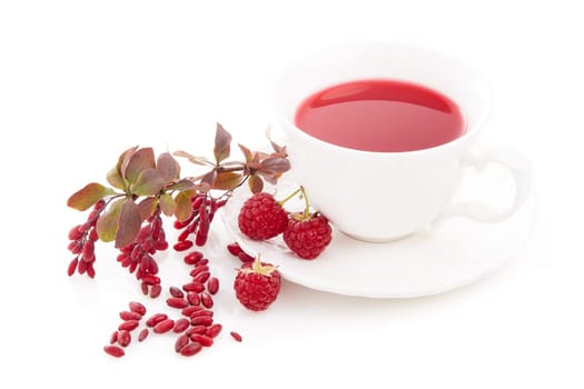 Healthy fruit tea with barberries and raspberries in white cup and branch of berberry isolated on white background.