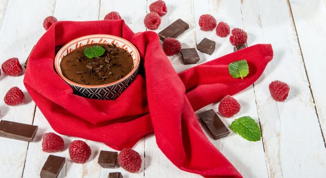 Homemade chocolate mousse with  raspberry on white wooden background