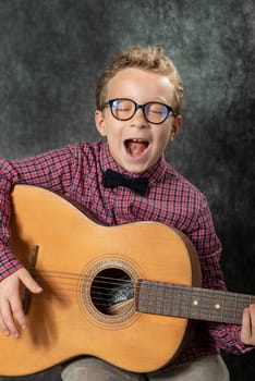 boy with a checkered shirt playing on acoustic guitar