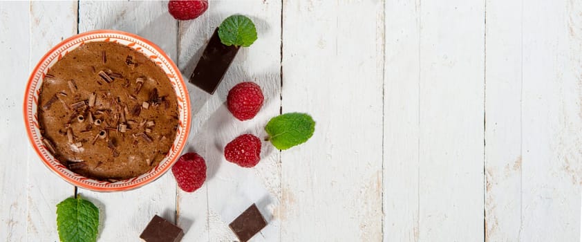 Homemade chocolate mousse with  raspberry on white wooden background