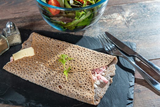 Breton crepe with cheese and bacon on the wooden background