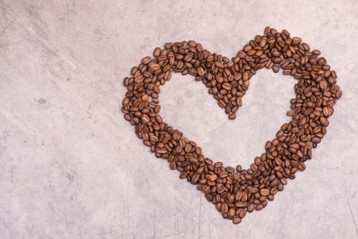 Roasted coffee beans on a brown textured background, hot drink ingredients