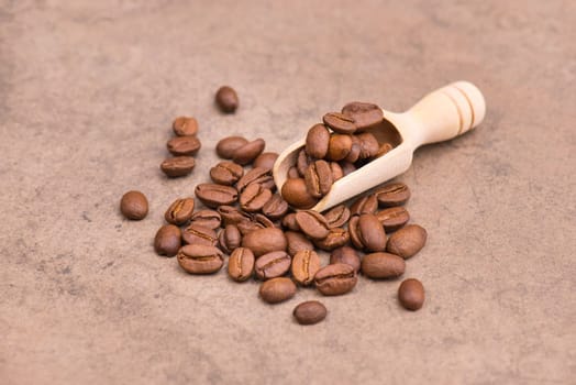 Roasted coffee beans on a brown textured background, hot drink ingredients