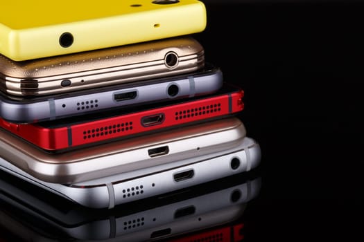 Heap of electronical devices close up - smartphones on black background