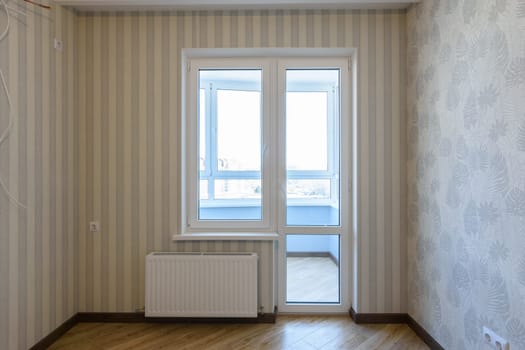 Exit to the balcony in the interior with plastic windows without furniture