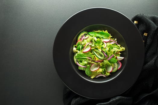 Healthy Green salad with fresh vegetables on dark table background