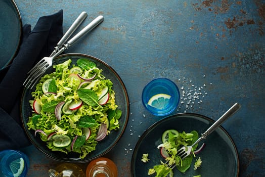 Healthy Green salad with fresh vegetables on blue table background