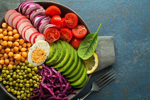 Healthy vegan lunch bowl. Avocado, chickpeas, tomato, red cabbage, green peas, red onion and radish vegetables salad. Healthy balanced vegetarian food concept Top view. Copy space