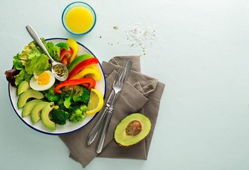 Healthy salad meal with quinoa, egg, avocado and mixed fresh vegetables on blue background top view. Food and health. Healthy meal concept