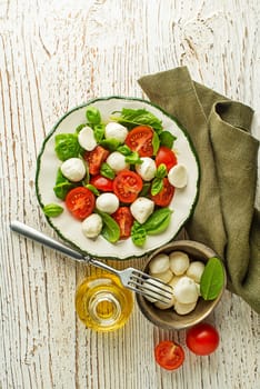 Delicious caprese salad with ripe tomatoes and mozzarella cheese with fresh basil leaves. Italian food. Salad with mozzarella, tomatoes, basil, salt, black pepper, olive oil