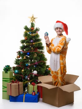 The girl stands in a box of Christmas tree toys dressing up the Christmas tree and looked cheerfully in the frame