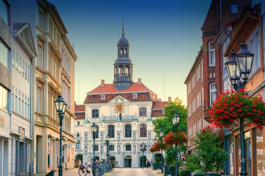 LÜNEBURG, NIEDERSACHSEN, GERMANY - JULI 27, 2018:.Vintage street lamp lantern with flowerbed. Historic city hall in the background in Lueneburg Germany.