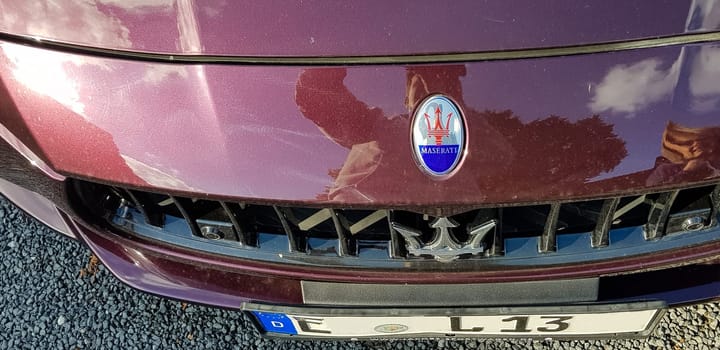 VELBERT, NRW, GERMANY - SEPTEMBER 07, 2018: bonnet with emblem and trademark of a Maserati in the car color claret.