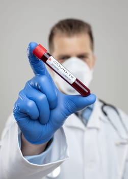 Doctor wearing respiratory mask and holding the Coronavirus Covid-19 blood sample