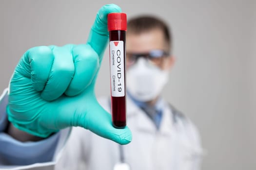 Doctor wearing respiratory mask and holding the Coronavirus Covid-19 blood sample