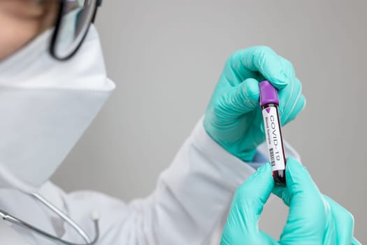 Doctor wearing respiratory mask and holding the Coronavirus Covid-19 blood sample