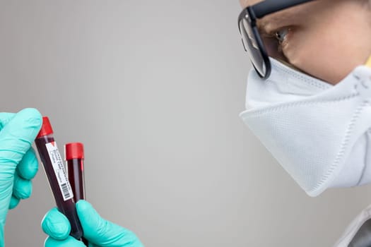 Doctor wearing respiratory mask and holding the Coronavirus Covid-19 blood sample