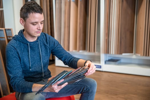 the man chooses the color of the new carpet according to the pattern book in the flooring shop.