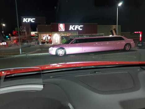 VELBERT, NRW, GERMANY - NOVEMBER 17, 2018:.A pink stretch limousine waits for the arrival of passengers in front of a Kentucky Fried Chicken restaurant in Velbert. Luxury vehicles and stretch limousines