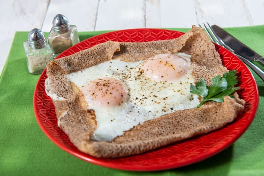 homemade Breton crepe with egg in a red plate