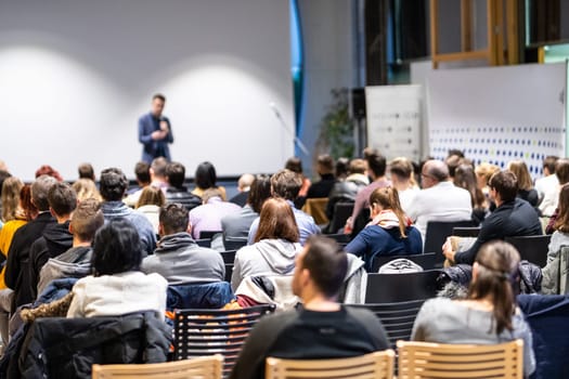 Speaker giving a talk in conference hall at business event. Rear view of unrecognizable people in audience at the conference hall. Business and entrepreneurship concept.