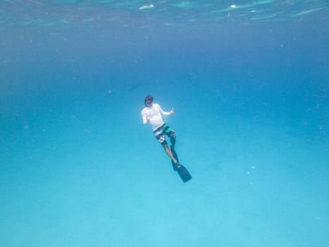 Underwater view of man free diving in blue ocean.