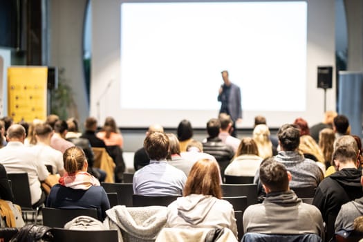 Speaker giving a talk in conference hall at business event. Audience at the conference hall. Business and Entrepreneurship concept. Focus on unrecognizable people in audience.