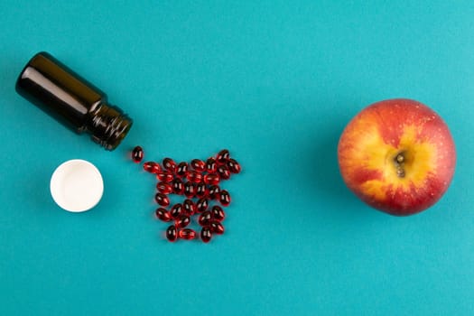 Red tablets are poured from a white plastic jar. Photo on blue background.